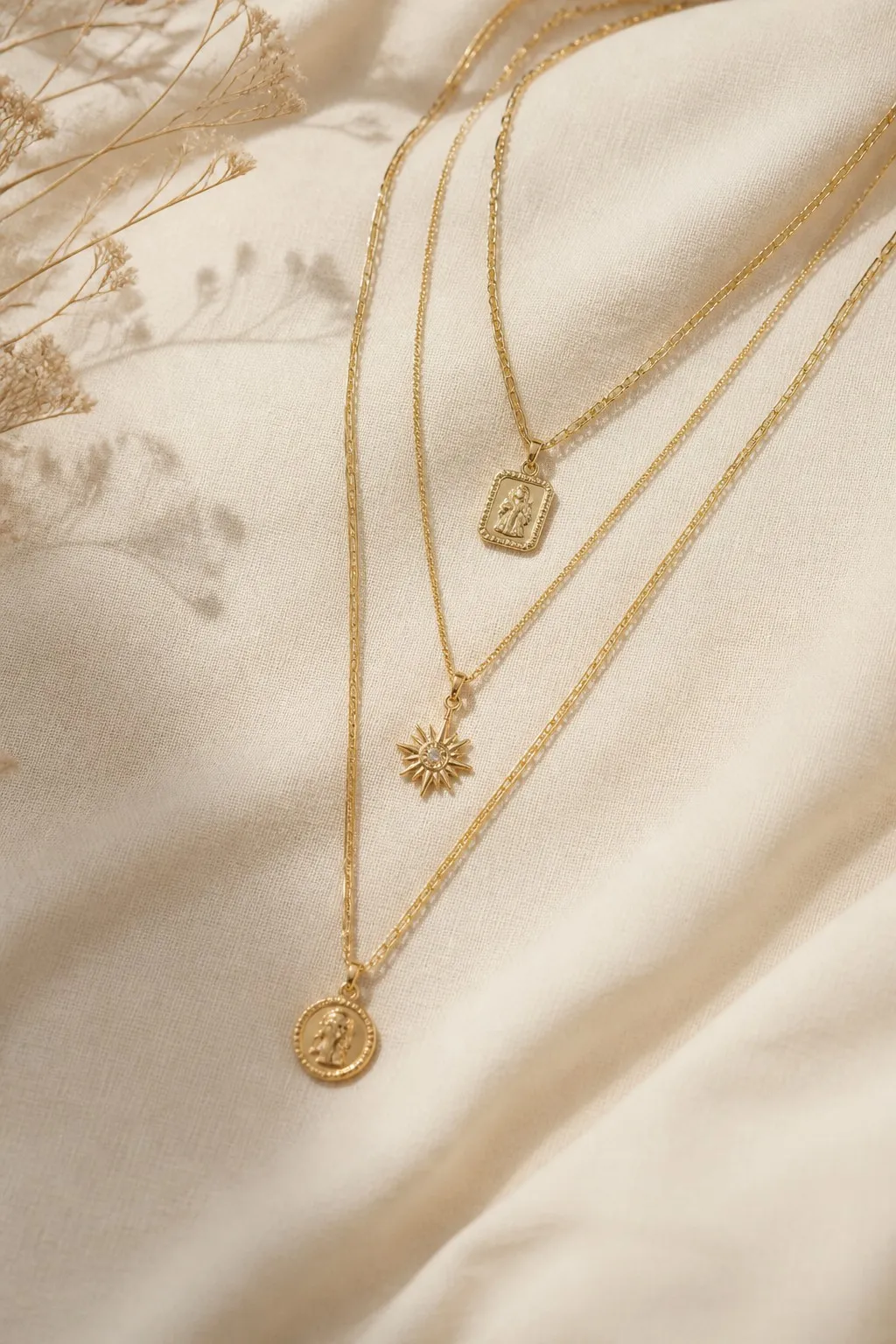 Layered gold necklaces on cream linen